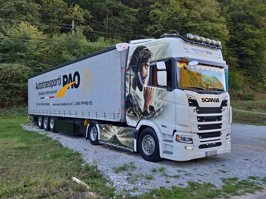 Camion Scania pictat cu o tema bisericeasca si semi-remorca cu prelata inscriptionata cu datele companiei